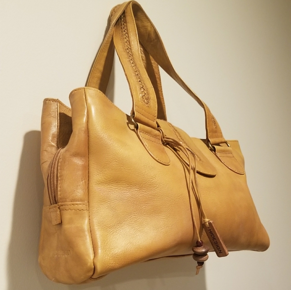 Tan leather hobo bag with braiding details and tassle